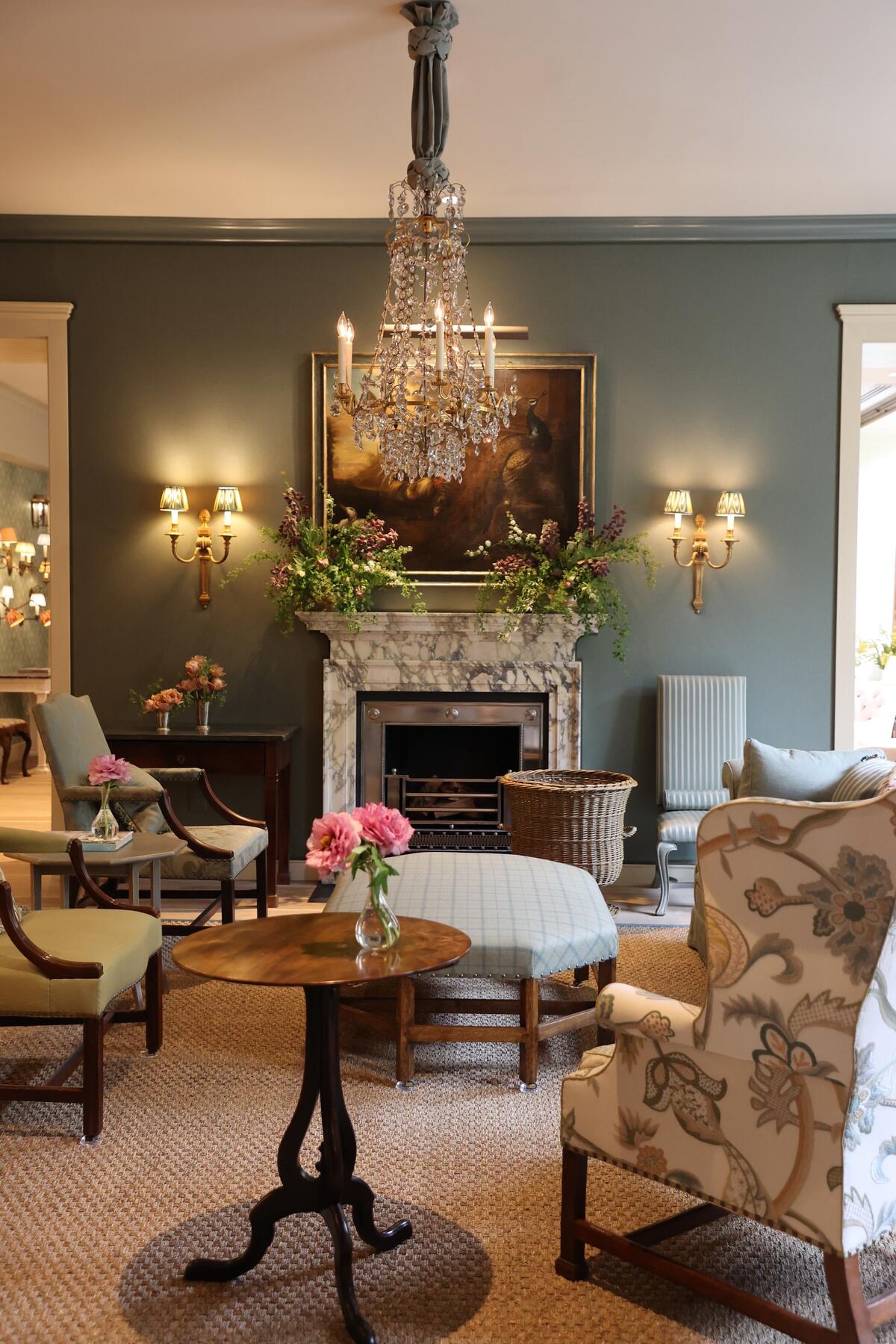The large sitting room with upholstered walls and a marble fireplace by London-based Jamb